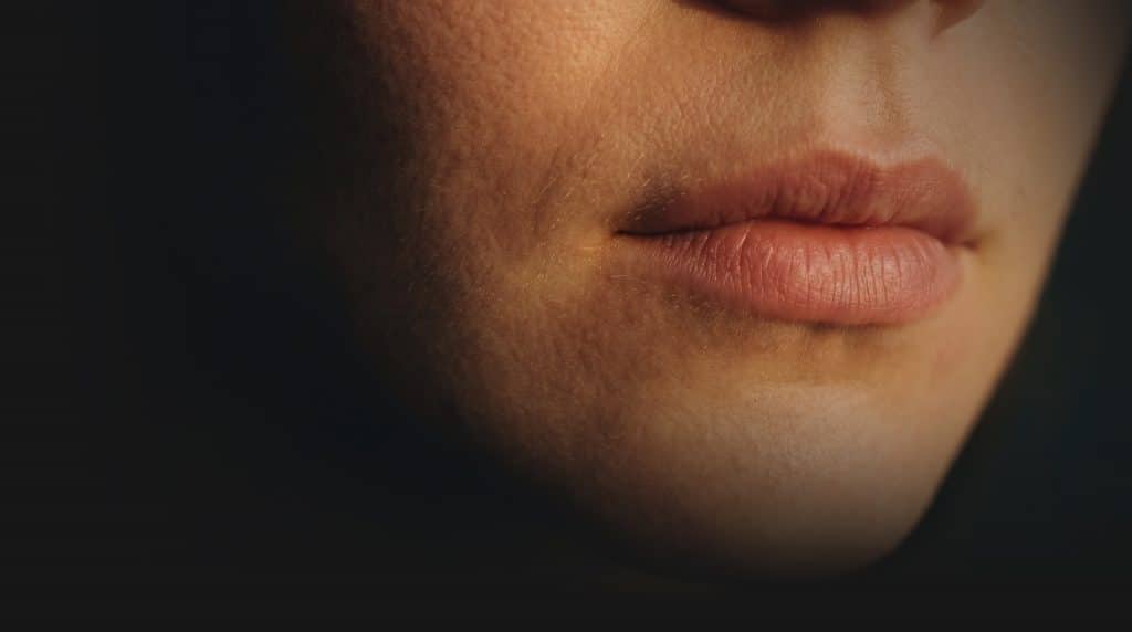 Extreme close-up of a woman's lips in warm dramatic lighting against a dark background